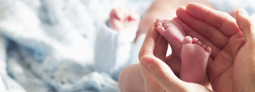 A mother holds her newborn baby's feet in her hands