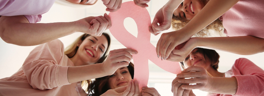 Several women hold a large pink ribbon