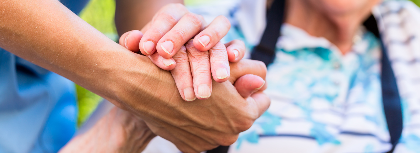 A caregiver holds hands with a patient