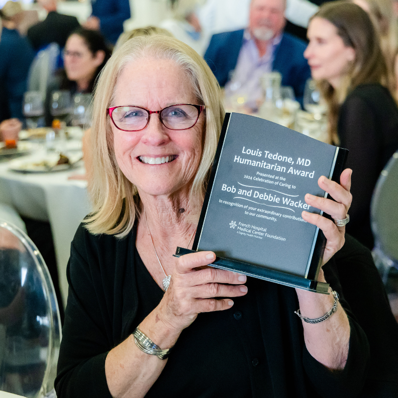 Portrait of Debbie Wacker holding the 2024 Louis Tedone MD Humanitarian Award at the 2024 Celebration of Caring