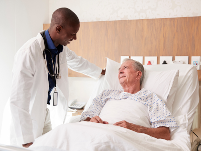 A male doctor talks to a male patient in a hospital bed