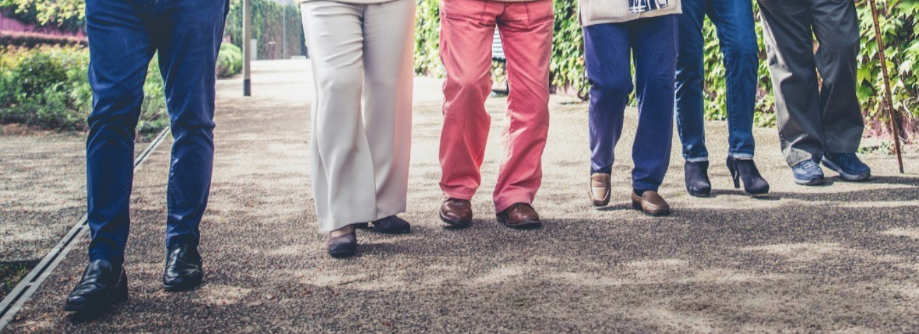Image of six people walking outdoors, showing their legs only