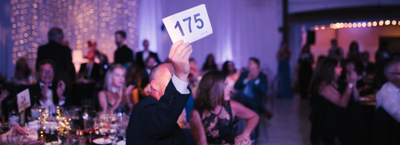 Guest at the Gala holds paddle to bid during the live auction