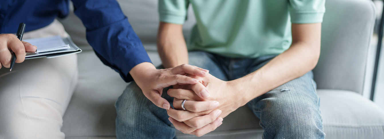 One person rests a comforting hand on the hands of another person One person rests a comforting hand on the hands of another person