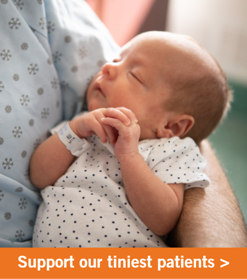 Image of a newborn baby being held in a hospital. Copy reads "Support our tiniest patients".