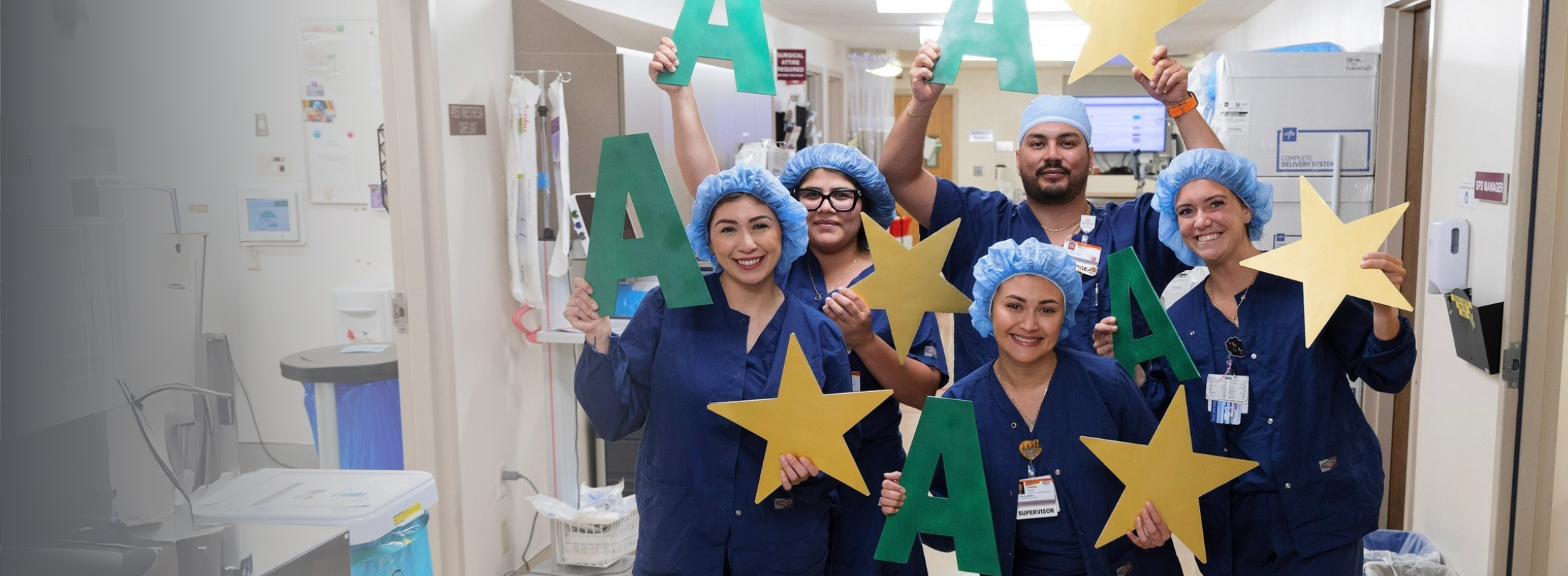 Five smiling French Hospital OR team members hold giant letter 