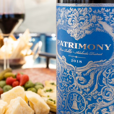 A bottle of Patrimony wine on a table with appetizers 