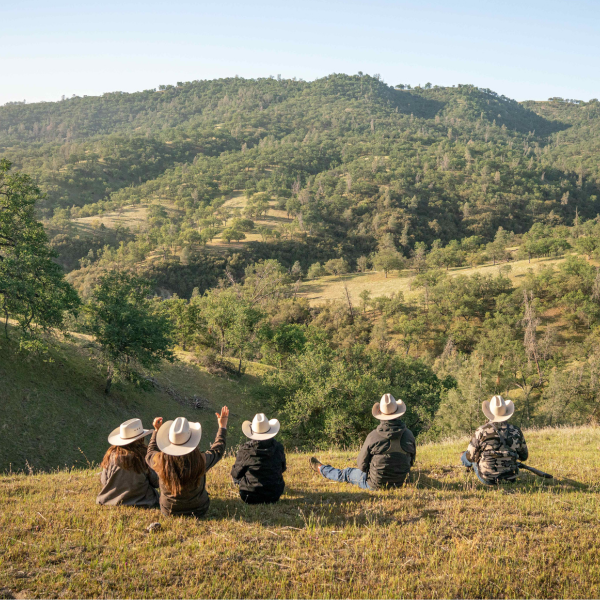Five people in cowboy hats sitting on a hill at Jack Ranch