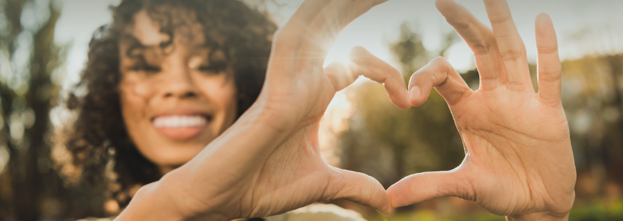 Smiling woman holds her hands up in a heart shape