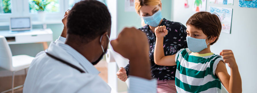 A little boy mimics a doctor's gesture with fists raised in victory