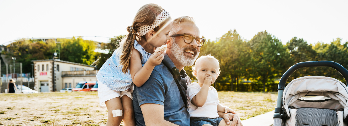 Grandfather sits with his two grandchildren outside